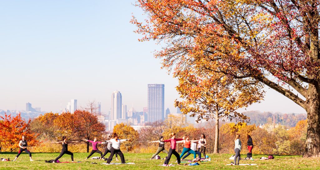 Pittsburgh, Pennsylvania — a group of women practicing yoga in the park, fall colors